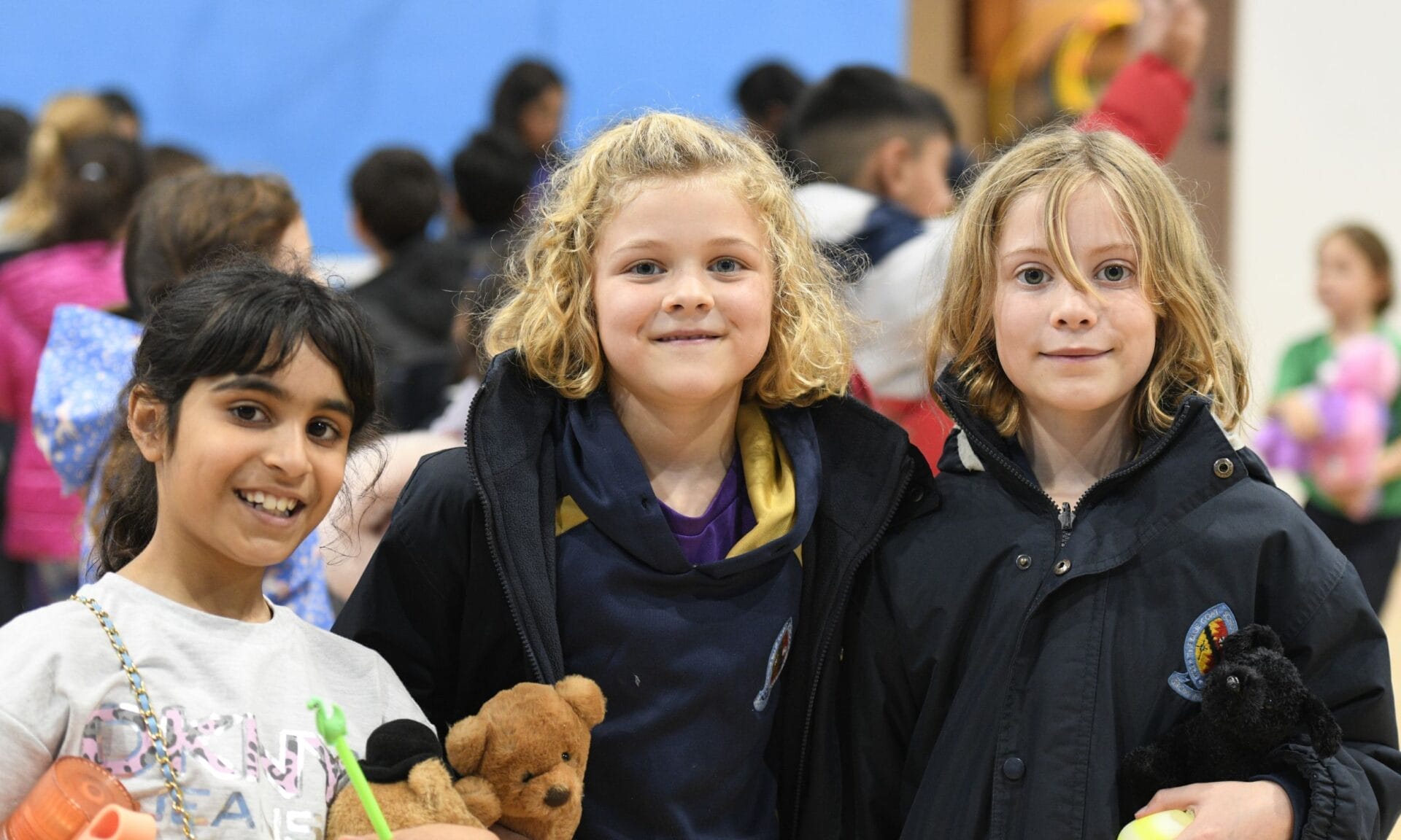 Three girls smile at the camera during Chandler and Grace House charity day.