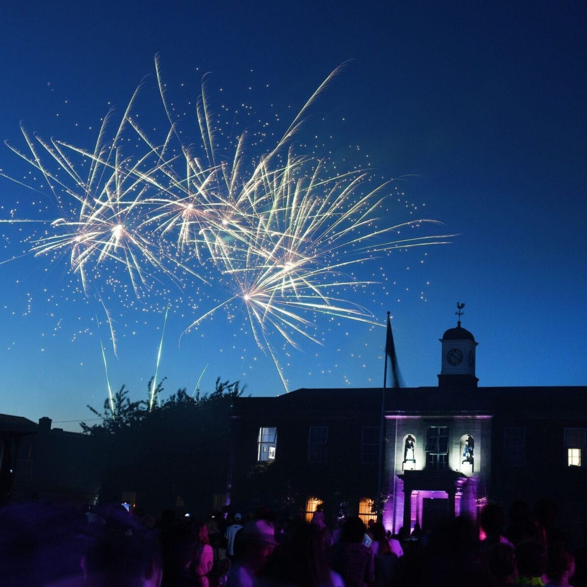 Fireworks exploding above the Blue Coat School entrance as people watch below in honour of the School's 300th anniversary