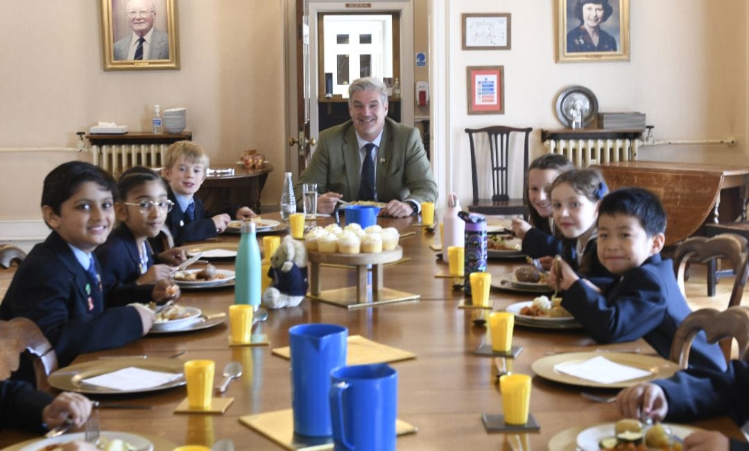 Pupils sit around the Boardroom table having lunch with the Headmaster, Mr Noel Neeson.