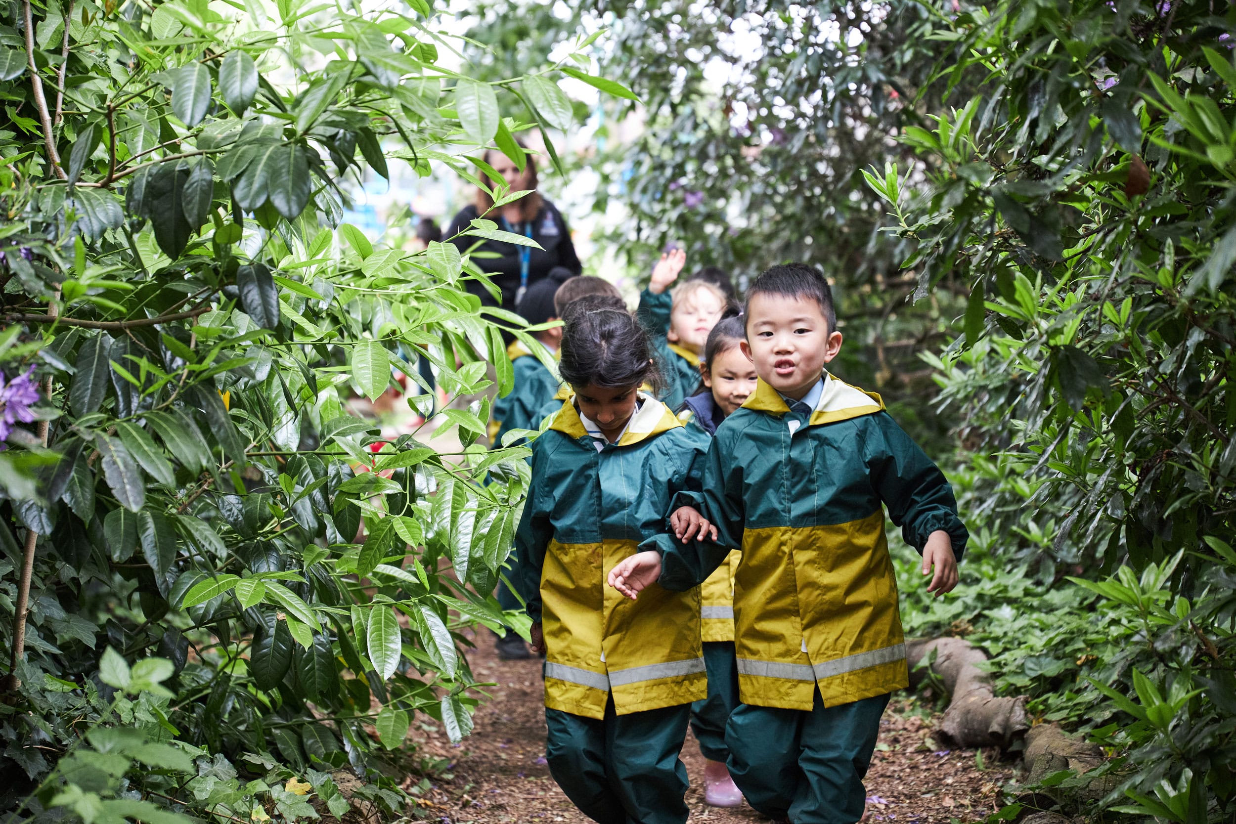 Children walking through the trees in Forest School.