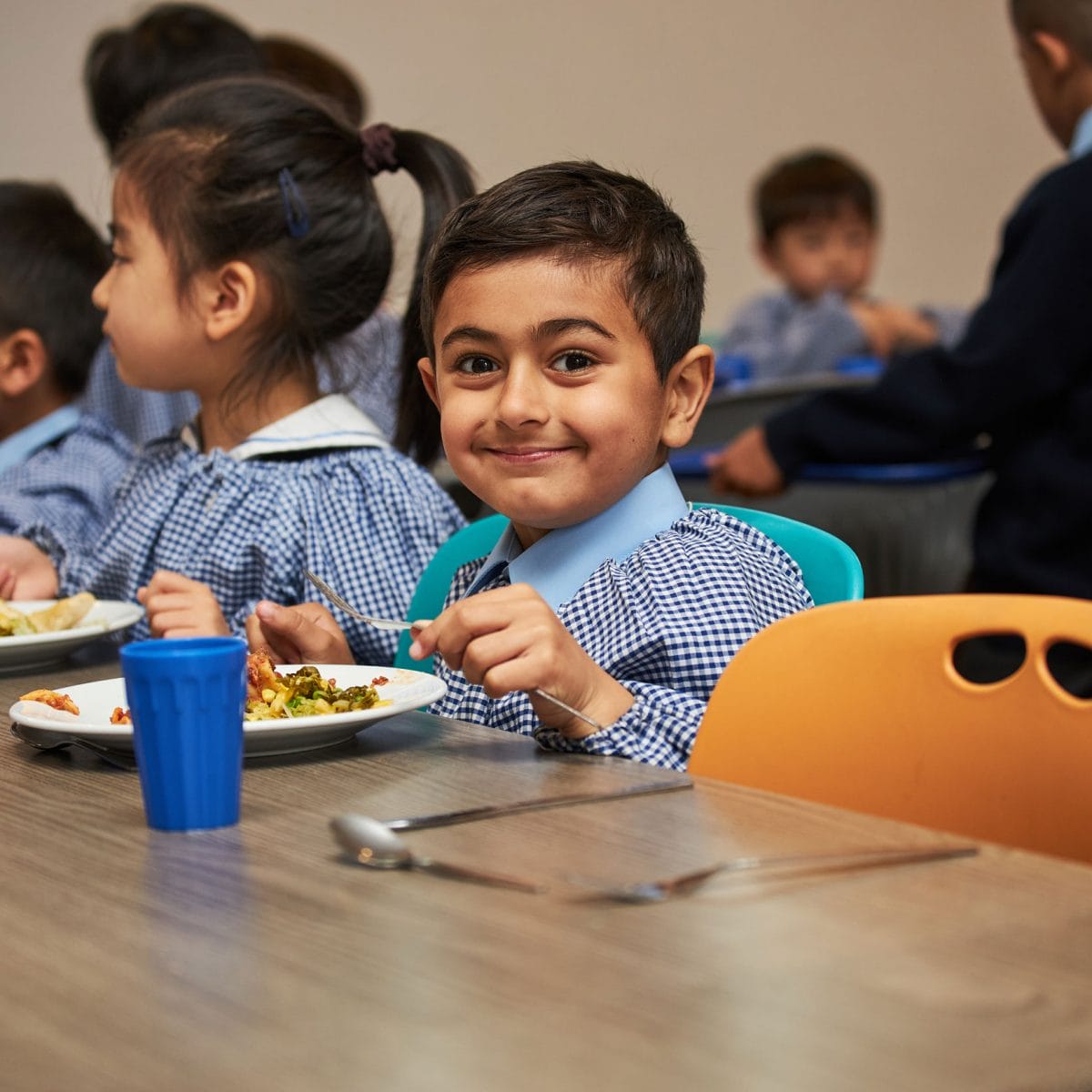 A boy looking at the camera which eating his lunch in The Blue Coat School Dining Hall.