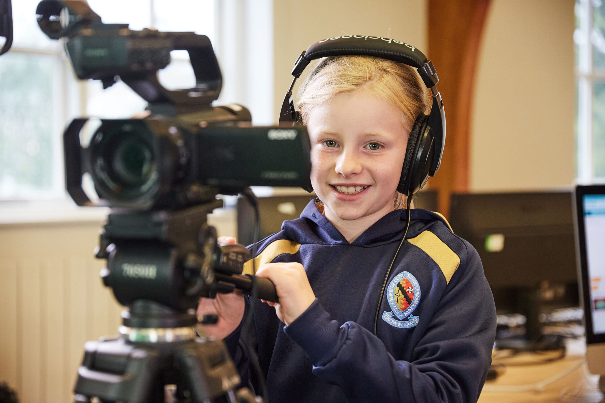 A girl using a camera with headphones on during a Computing lesson at The Blue Coat School.