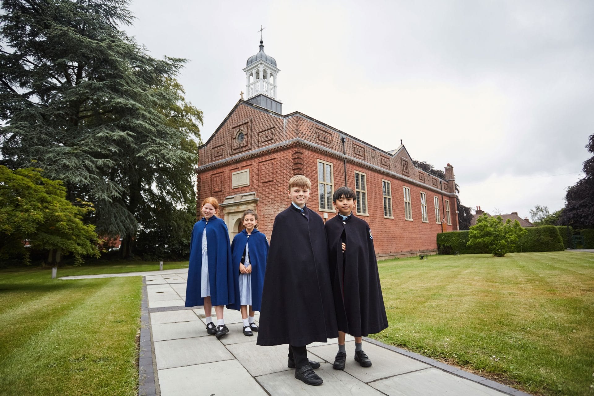 Pupils wearing their best blue cloaks walking outside the front of the Chapel at The Blue Coat School.