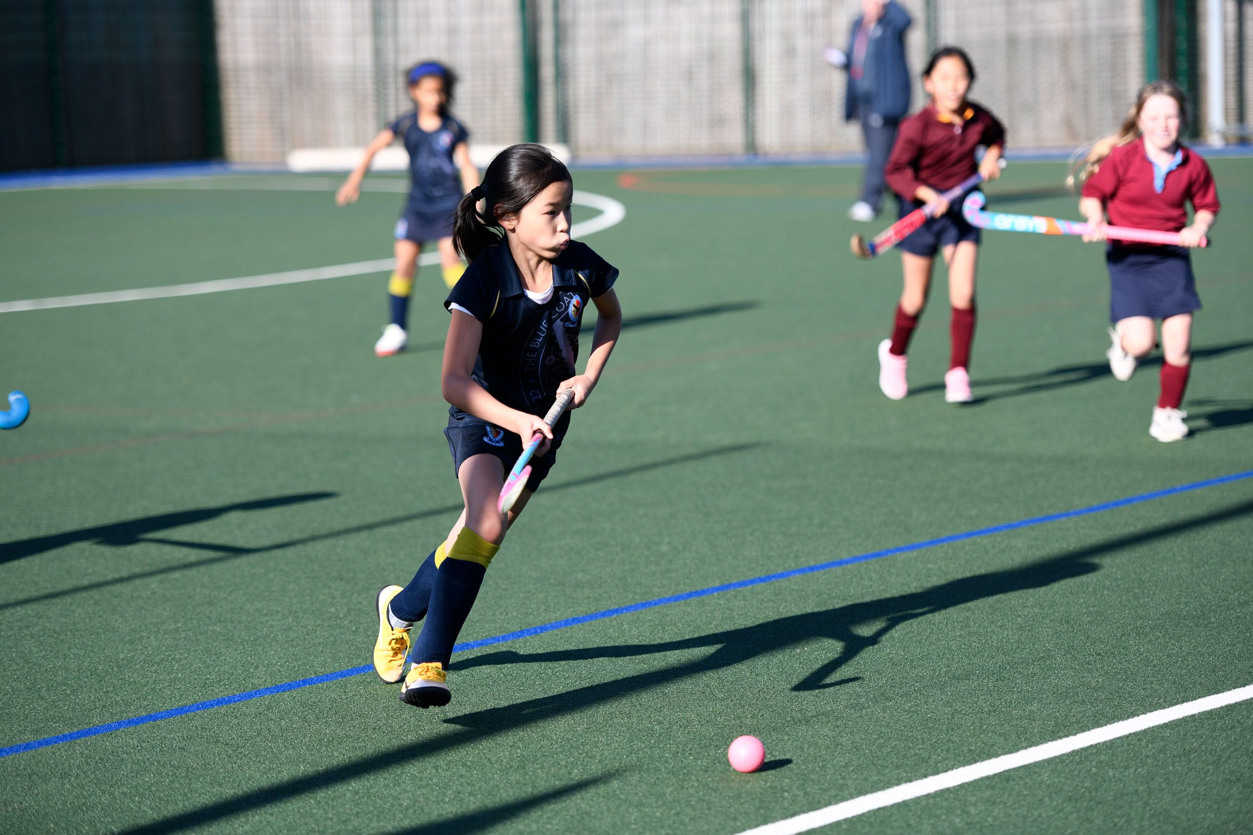 A girl dribbles the ball playing hockey on The Blue Coat School's AstroTurf pitch.