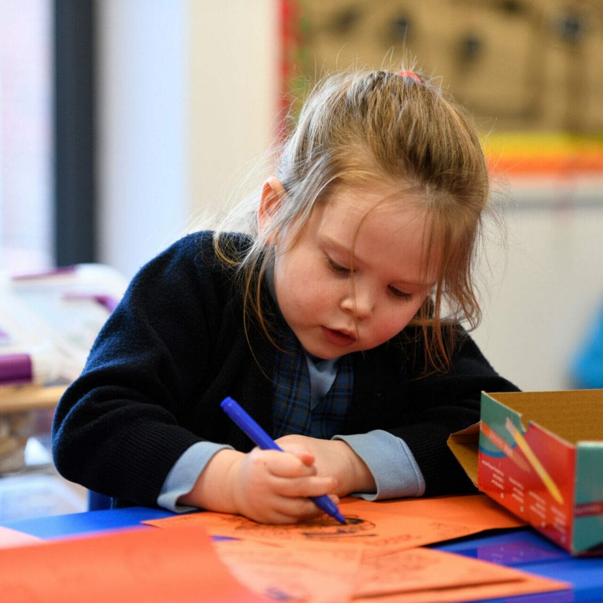 A girl in Pre-Prep drawing on a piece of paper.