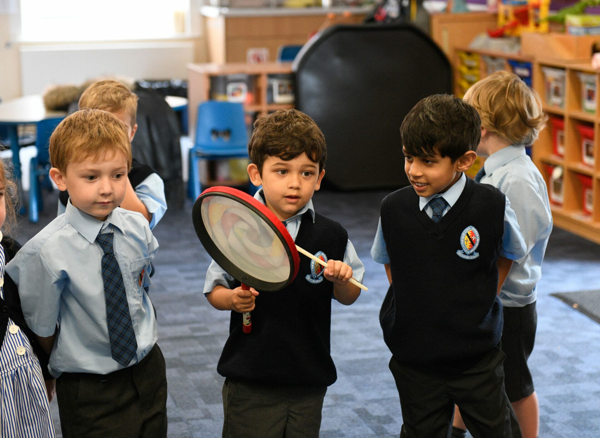 A boy is playing a tambourine in the Pre-Prep music room.