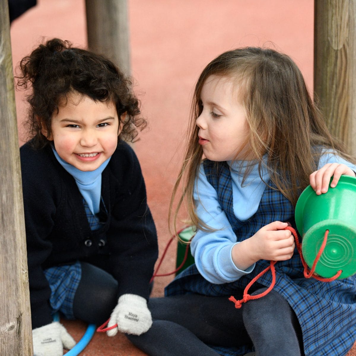 Two Nursery girls playing with a bucket in the playground at The Blue Coat School.