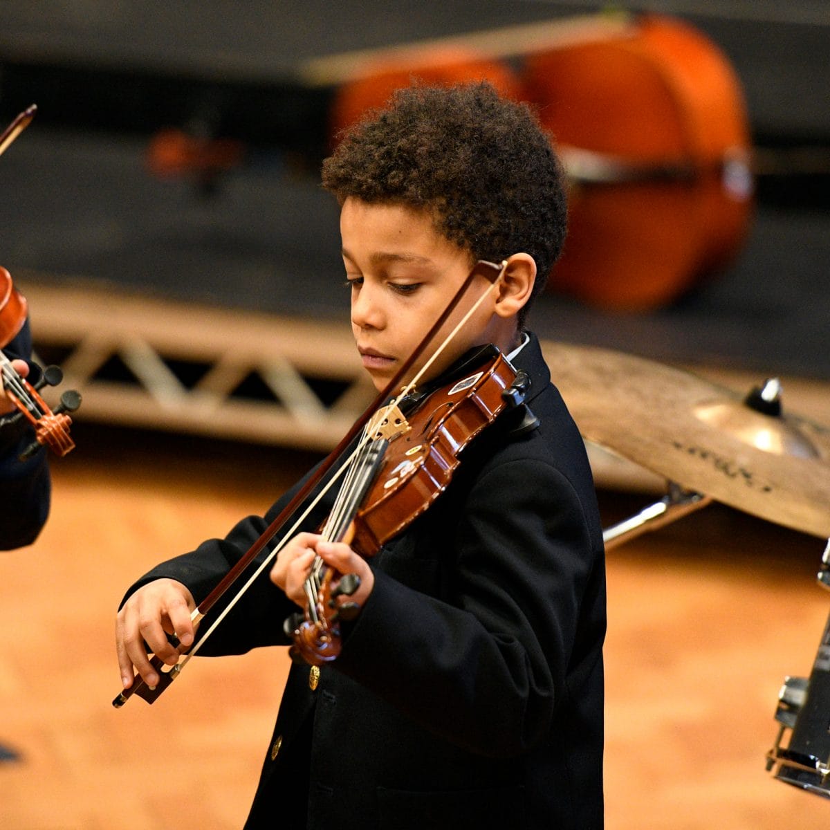 A boy playing the violin at a concert.