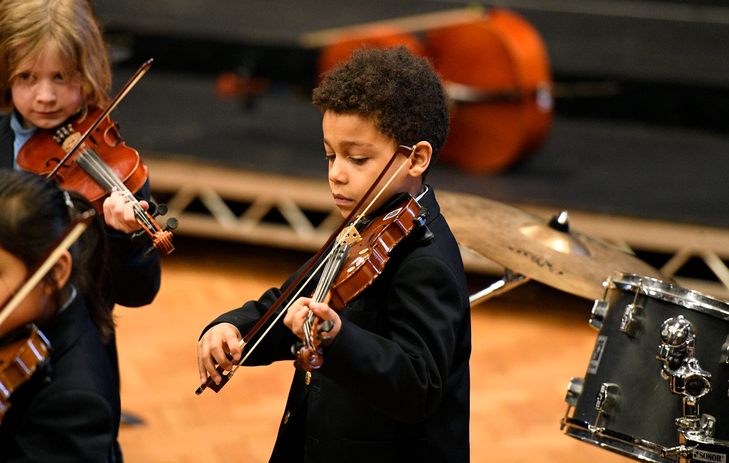 A boy playing the violin at a concert.