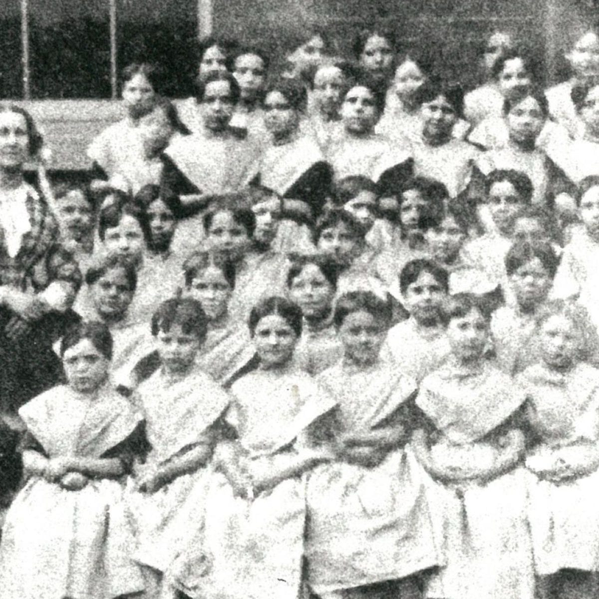 Rows of girls sitting for a photo with two teachers along the side in 1855