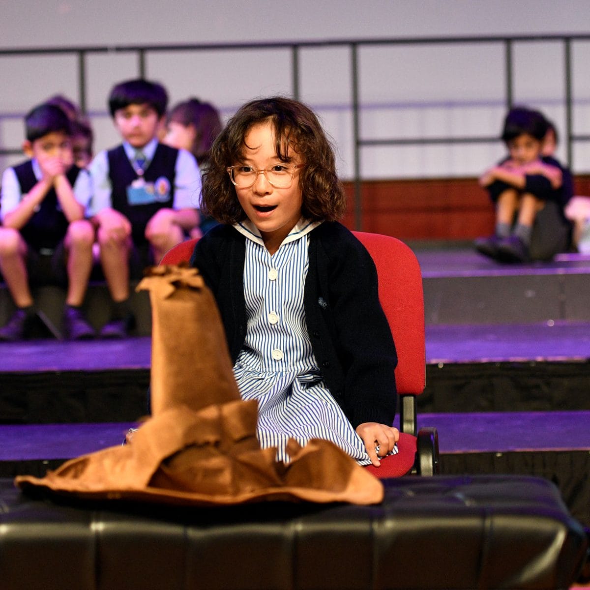 A girl sits in front of the sorting hat at the House Sorting Ceremony.