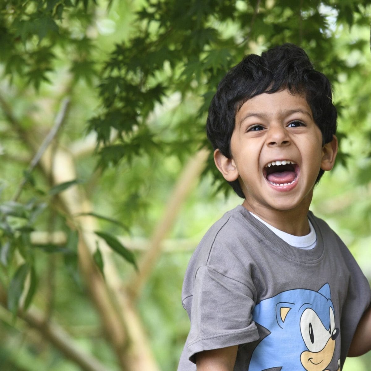 A boy playing in the trees at the Forest School Experience, a welcome event for children joining The Blue Coat School.