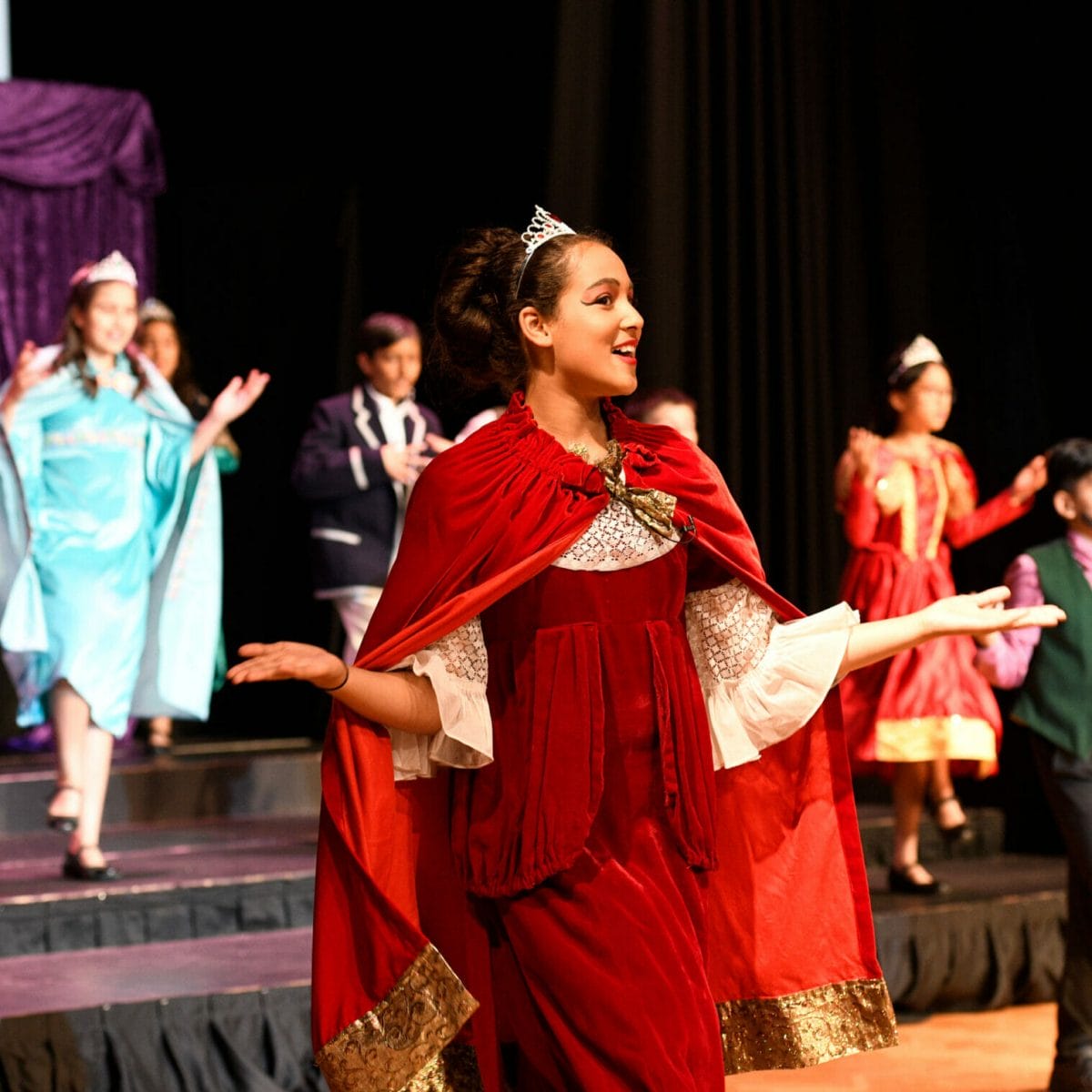 A girl dressed in red robes plays the Queen in the Year 6 play.
