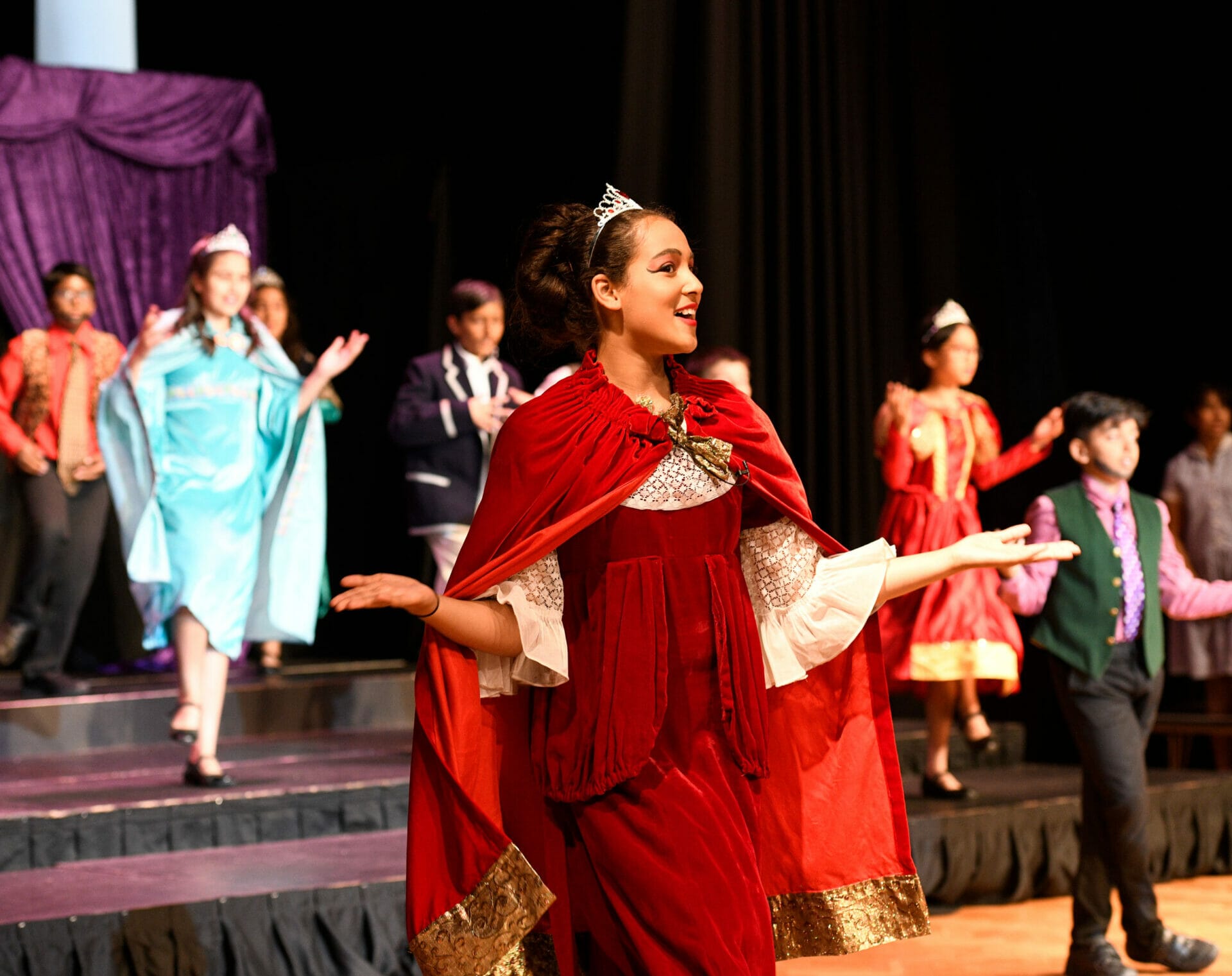 A girl dressed in red robes plays the Queen in the Year 6 play.